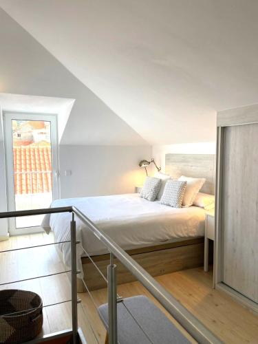 a white bedroom with a bed with pillows on it at Don Sebastiao in Sesimbra
