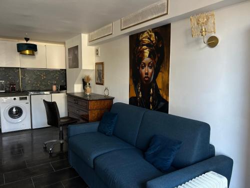 a living room with a blue couch and a kitchen at Résidence P&C Studio élégant proche Paris - Neuilly-sur-Marne in Neuilly-sur-Marne