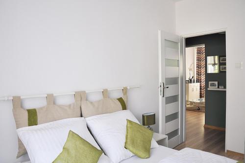 - une chambre avec un lit doté de draps blancs et d'oreillers verts dans l'établissement Apartament Rosa, à Jelenia Góra