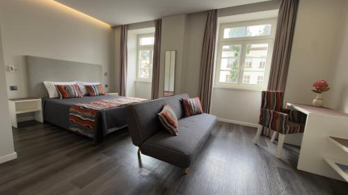 a bedroom with a bed and a chair and window at Gold Center Funchal 101 in Funchal