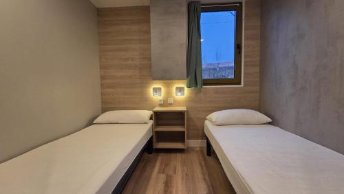 two beds in a small room with a window at Camping Bungalows Mariola in Bocairent