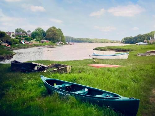 a group of boats sitting on the grass next to a river at Oystercatcher Cottage in Haverfordwest