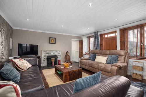 a living room with leather furniture and a fireplace at Historic 4BR Home - The Old Bakehouse in Llandysul