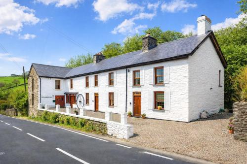 a white house on the side of a road at Historic 4BR Home - The Old Bakehouse in Llandysul