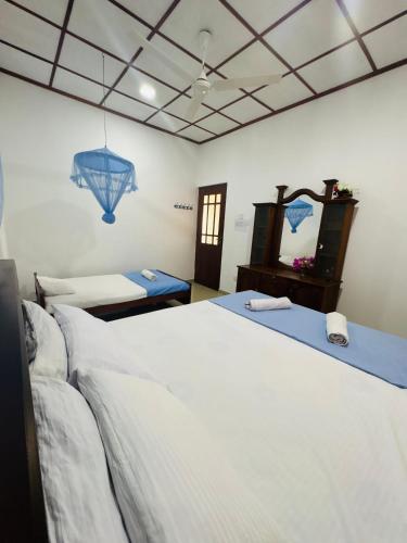 a bedroom with a large white bed and a mirror at Fourcoock Villa in Kosgoda