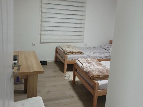 a room with two beds and a table and a window at Soba Ðorović 3 in Postenje