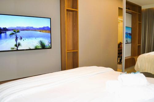 Un dormitorio con una cama y un televisor de pantalla plana. en Centro Compact Life, en Goiânia