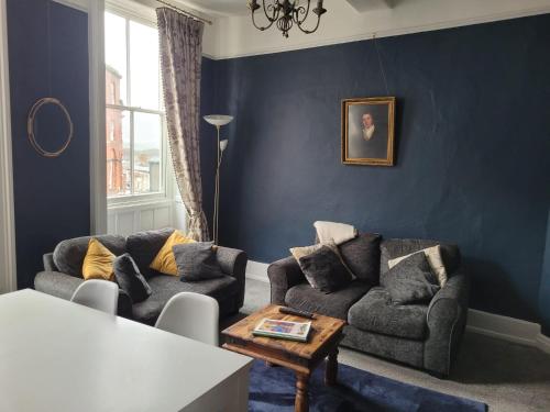 a blue living room with two couches and a table at The Gingernut in Ross on Wye