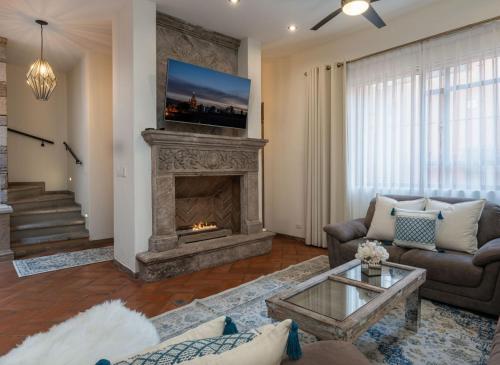 a living room with a fireplace and a couch at Casa del Palmar, Elegant 3BR Home with Rooftop in Centro San Miguel in San Miguel de Allende