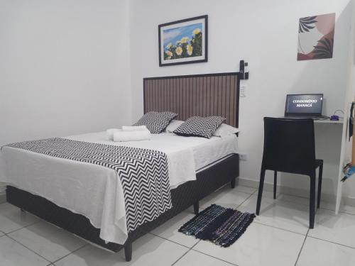 a bedroom with a bed and a table and a chair at Condomínio Flamboyant in Pindamonhangaba