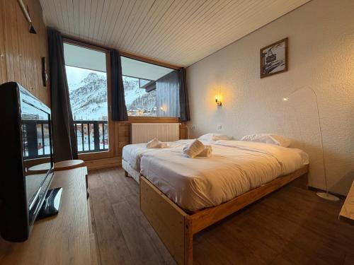 une chambre avec un lit et une grande fenêtre dans l'établissement Studio centre Val d'Isere, à Val dʼIsère