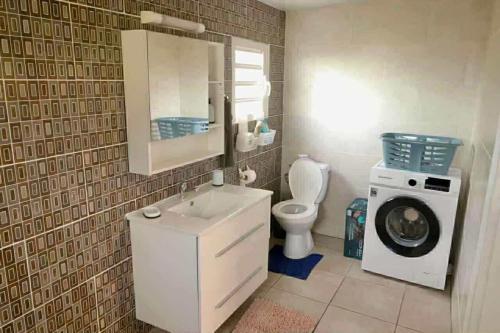 a bathroom with a washing machine and a sink at La Maison des Cocotiers in Petite Île