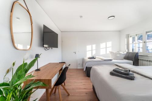 a bedroom with two beds and a desk and a mirror at Check-In by BeOne RW-N in Rottweil