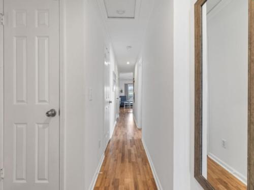 a hallway with white walls and a mirror and wood floors at Sea The Good condo in Carolina Beach