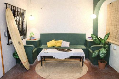 a living room with a green couch and a surfboard at Olivo Hostel, Punta Zicatela in Puerto Escondido