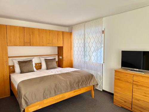 a bedroom with a bed and a flat screen tv at Appartements Waldrose in Titisee-Neustadt