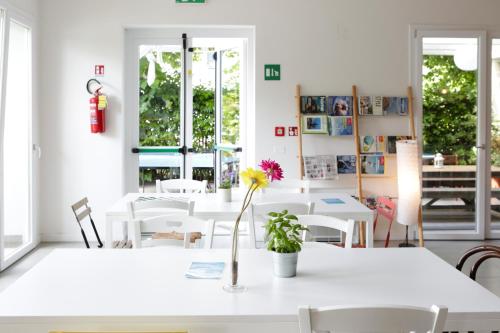 a room with tables and chairs and a flower in a vase at Ostello Meet Gardalake Hostel in Peschiera del Garda