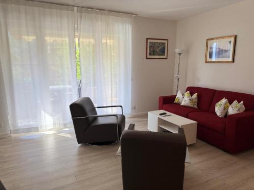 a living room with a red couch and a chair at Ascona: ORTO DEGLI ANGIOLI in Ascona