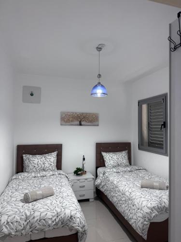 two beds in a room with white walls at Royal Park A&7 Deluxe, swim pool - by G&P suites in Eilat