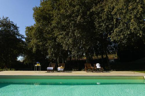 two people sitting in chairs next to a swimming pool at Quinta Das Essências in Penafiel