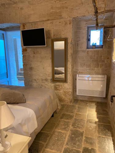 a bedroom with a bed and a mirror and a television at Trulli diffusi de La Corte dell'Astore I Trulli Antichi Mestieri in Alberobello