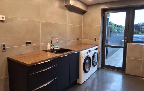 a kitchen with a sink and a washing machine at Penthouse by Krambatangi in Øravík