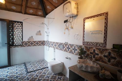 a bathroom with a toilet and a mirror at Mud & Meadows- A Satvik Farmstay, Jamshedpur in Jamshedpur
