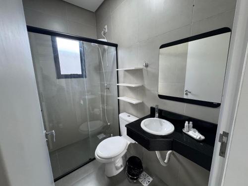a bathroom with a toilet and a sink and a shower at Condomínio Noruega - casas 2 dormitórios in Jaguarão