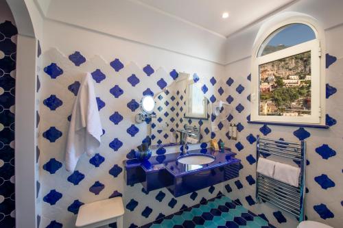a blue and white bathroom with a sink and a mirror at Hotel Reginella in Positano