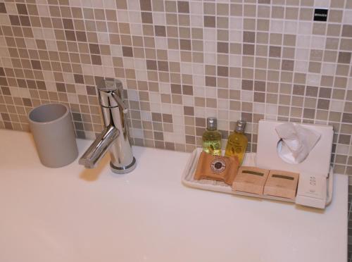 a bathroom counter with a sink with soap and bottles at B&B Milu' in Crotone