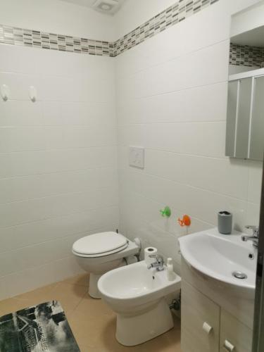 a white bathroom with a toilet and a sink at Alloggio del Barbarossa in Acquapendente