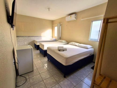 a hotel room with two beds and a television at Pousada Dom Manuel - Ce in Fortaleza
