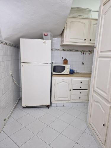a white kitchen with a refrigerator and a microwave at Dar Mima in Tunis