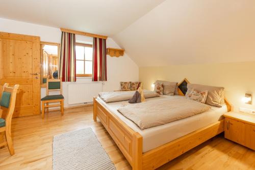 a bedroom with a bed and a chair and a window at Dorfergut in Weisspriach