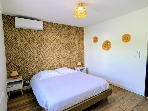a bedroom with a white bed and a wall at Villa Le Nid du Pont d'Arc in Vallon-Pont-dʼArc