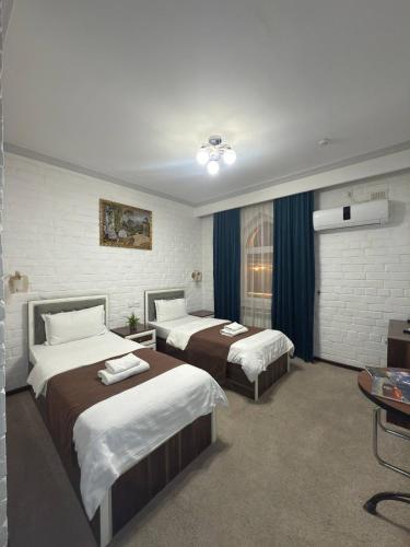 a hotel room with two beds and a tv at Almaz PLAZA in Tashkent