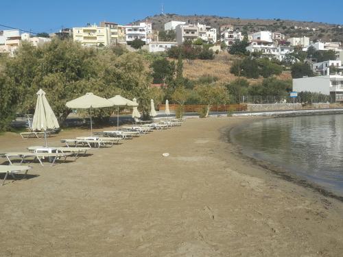 a beach with tables and chairs and umbrellas and the water at Elounda Sea Suites in Elounda