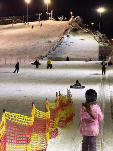 a young girl standing in front of a ski slope at night at Happy rooms in Ventspils