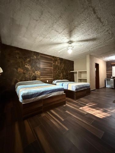 Zwei Betten in einem großen Zimmer mit Holzboden in der Unterkunft Mi ranchito samao in Chichicasta