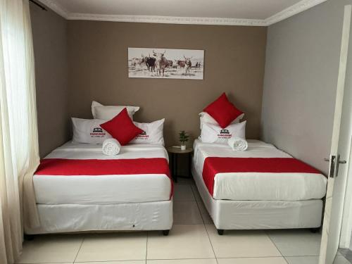 two beds in a room with red and white pillows at Kangumine Self Catering Units in Okakarara