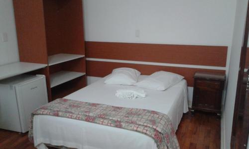 a hotel room with a bed with white sheets at MOVA Hotel D'oeste - Localizado em frente a Praça Principal da Cidade, na área Central - Pé na Praça in Poços de Caldas