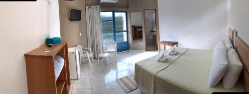 a bedroom with a bed and a table and a room at Pousada Camping Quedasdagua in Barra do Rio Abaixo