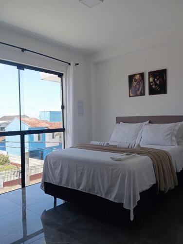 a bedroom with a large bed and a large window at Suíte 25 vista para o mar in Pontal do Paraná