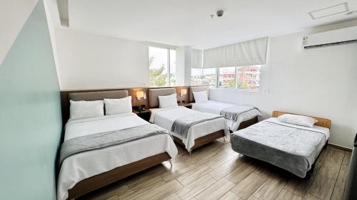 a room with two beds and a couch and a window at Hotel Puerto Pacifico Guayaquil Airport in Guayaquil