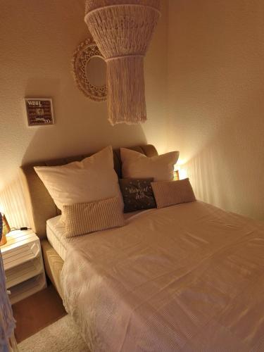 a bedroom with a bed with pillows and a chandelier at Linnis Strandhaus in Garrel