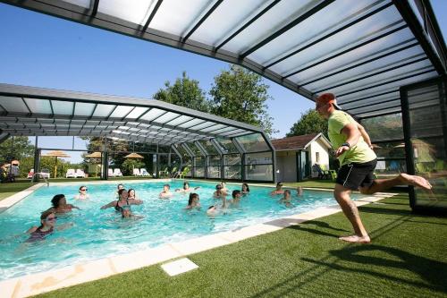 a man running in a swimming pool with a group of people at ZEcamping 4 étoiles animaux acceptés piscine couverte in Loupiac