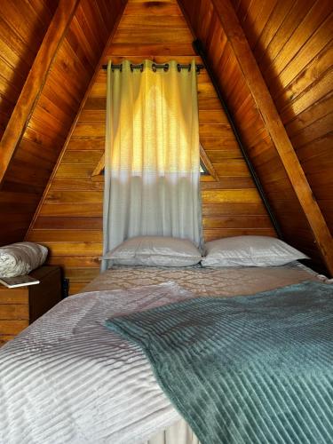 a bed in a wooden cabin with a window at Chalé Nascer do Sol 2 in Massaranduba