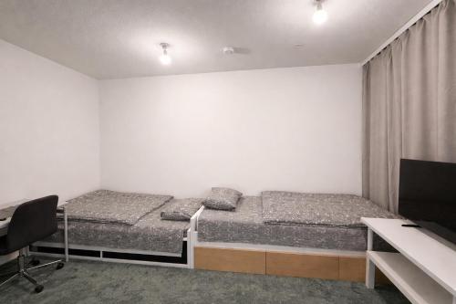 two beds in a room with a desk and a computer at City Heaven in Turku