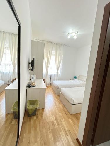 a white bedroom with two beds and a mirror at Affittacamere Seveso in Milan