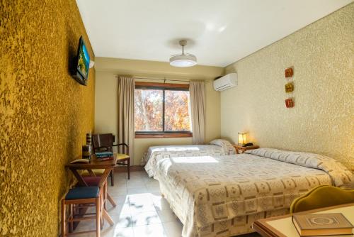 a hotel room with two beds and a window at Hotel Xumec Mendoza Centro in Mendoza